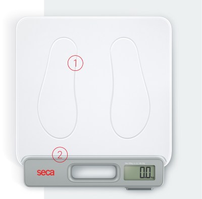 Una vista de cerca de una báscula digital seca (seca 874+) que muestra áreas destacadas con círculos rojos y números. El primer círculo, marcado como '1', resalta los contornos de las huellas en la superficie blanca. El segundo círculo, marcado como '2', resalta el asa incorporada ubicada debajo de las huellas y al lado de la pantalla digital. La pantalla muestra '0,0 kg', y el nombre de la marca 'seca' es visible en rojo a la izquierda del asa.